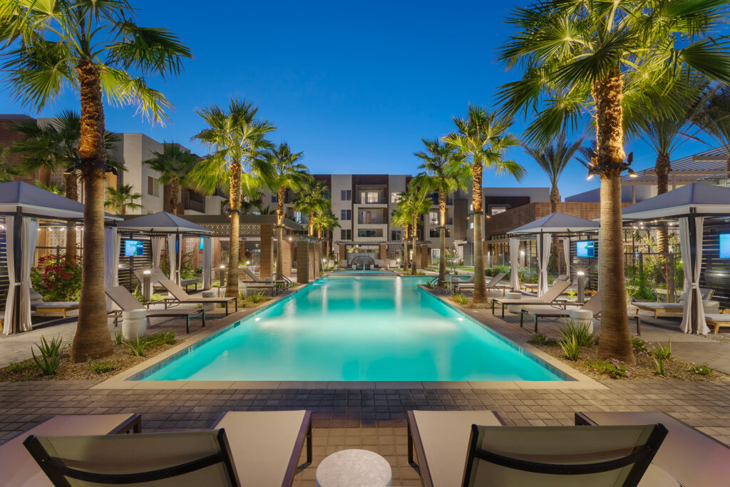 Resort-style pool at dusk with private cabanas and palm trees at Town Chandler in Chandler, AZ